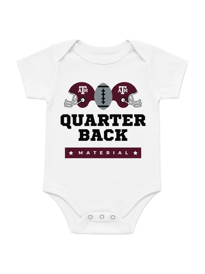A white short-sleeve baby bodysuit featuring a maroon and gray Texas A&M football graphic with the text 'QUARTER BACK' and 'MATERIAL'.